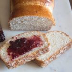 milk bread with two slices one has strawberry jam on it
