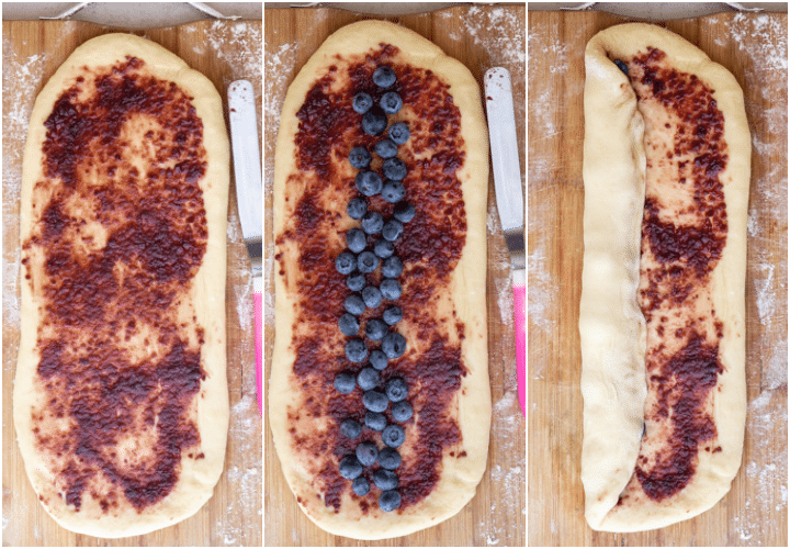 spreading jam on the oval, blueberries on the oval and starting to roll up on a wooden board