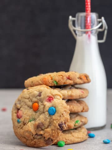 5 cookies stacked with 1 leaning and a bottle of milk.
