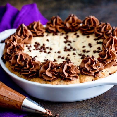 a cookie pie with frosting in a white pan.