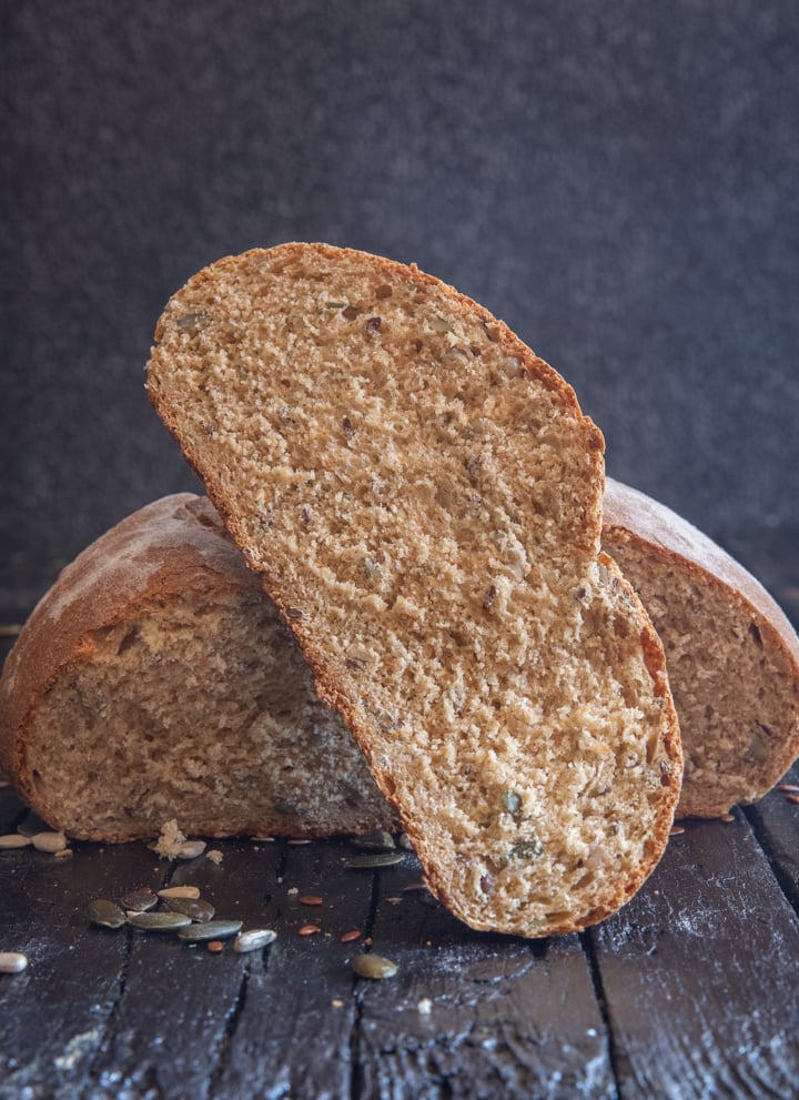 A slice of seed bread leaning on the loaf.