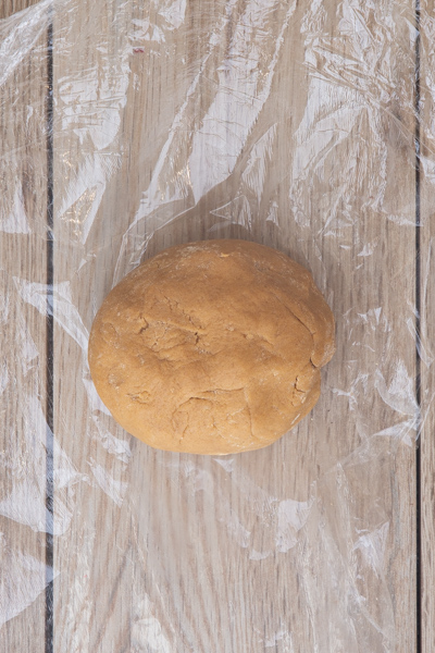 Dough formed into a ball on plastic wrap.